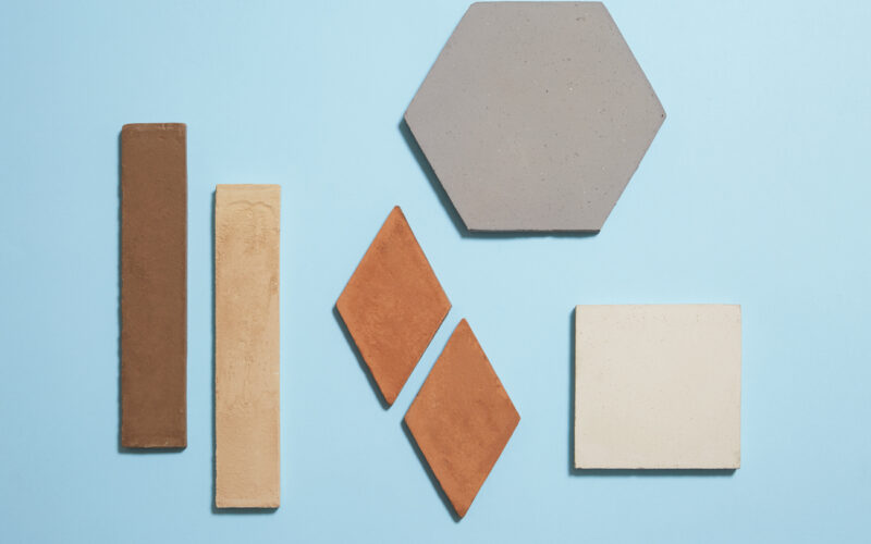 Diverse piastrelle di ceramica di varie forme e colori su sfondo blu.
