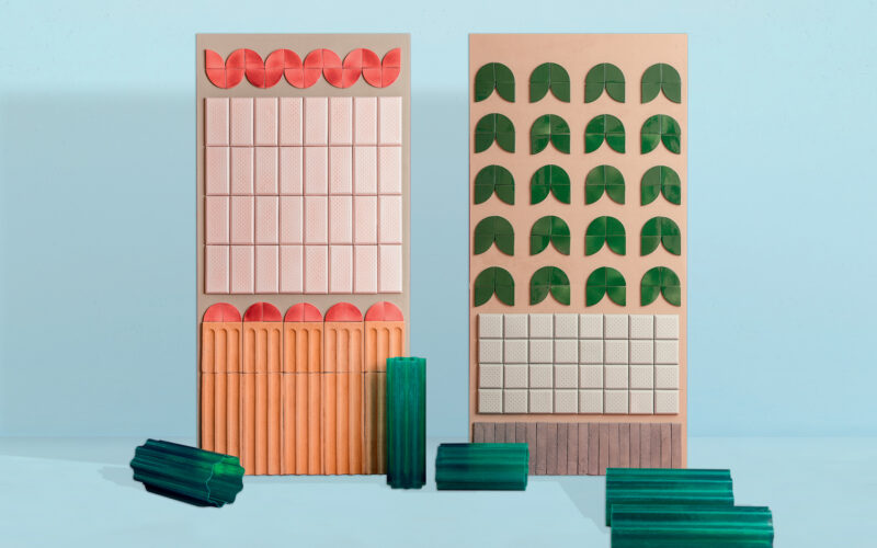 Diverse piastrelle in ceramica di vari colori e forme, come rettangolari, quadrate e semicircolari, disposte su uno sfondo blu.