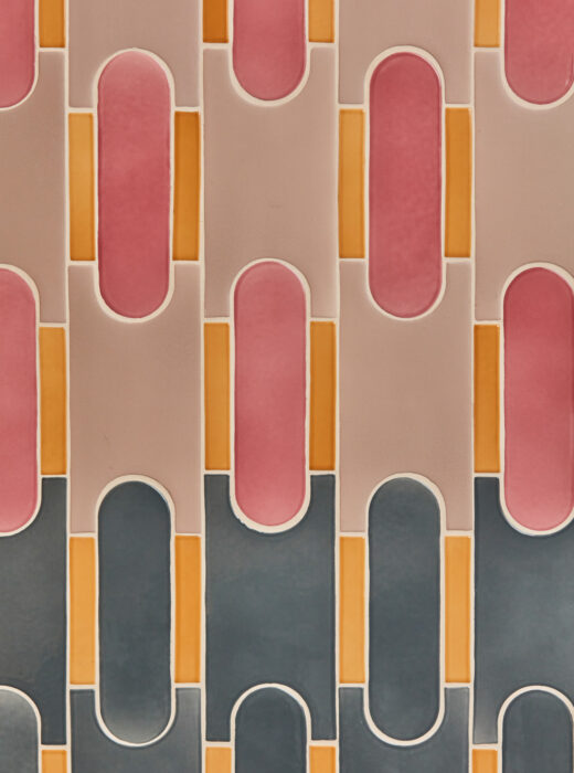 Rivestimento murale con piastrelle rosa, arancioni e grigie a forma di H.