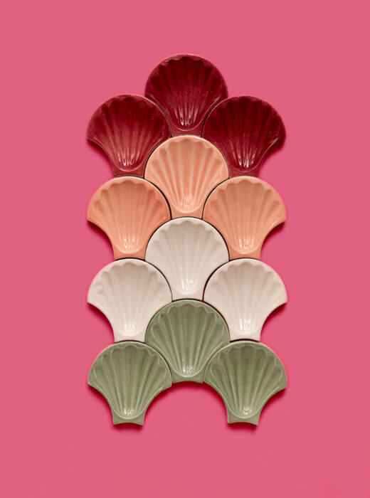 Piastrelle a forma di conchiglia in vari colori su sfondo rosa.