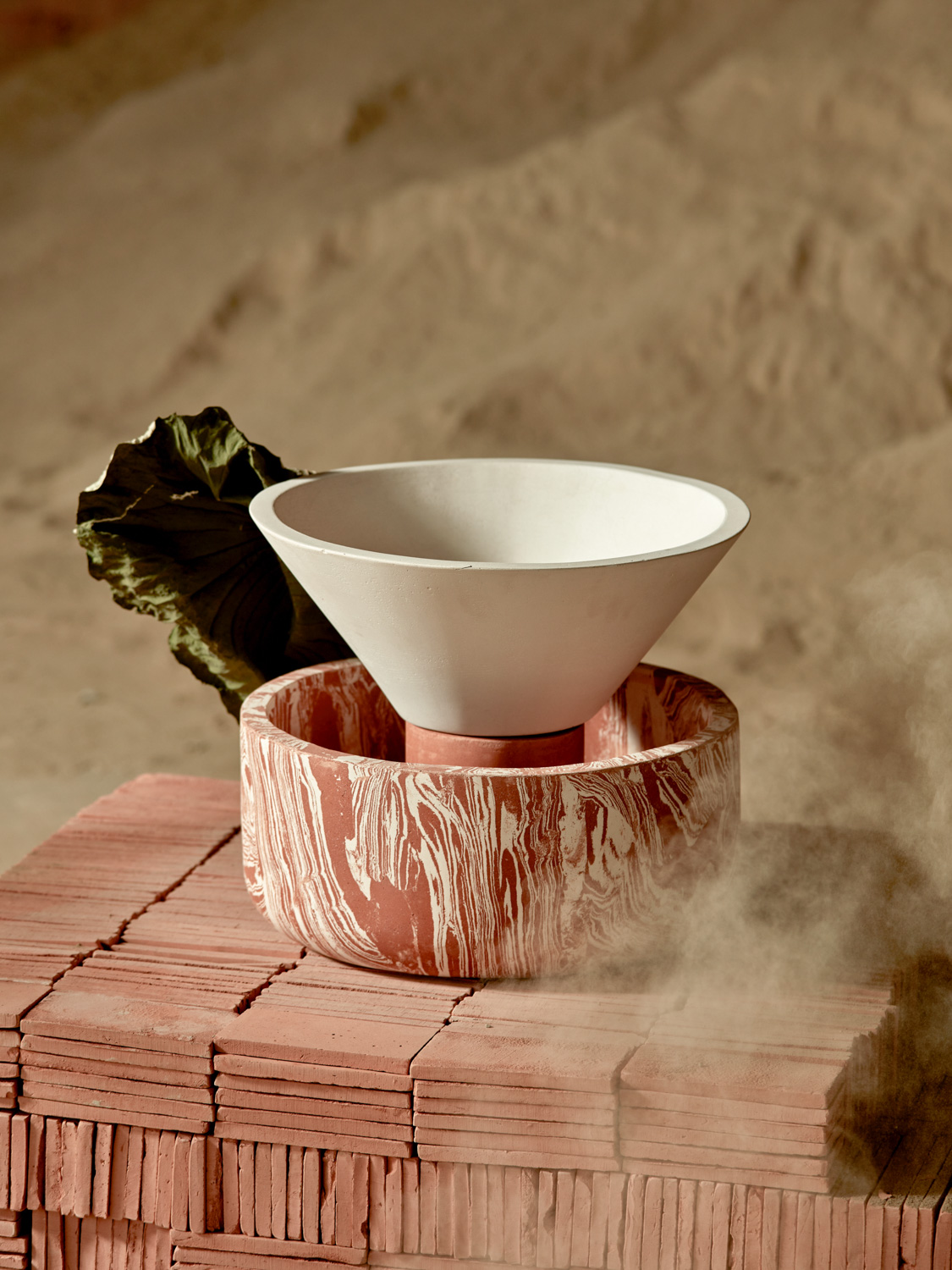 Scultura in ceramica bianca e marmorizzata rossa su blocchi di terracotta, con foglia decorativa sullo sfondo