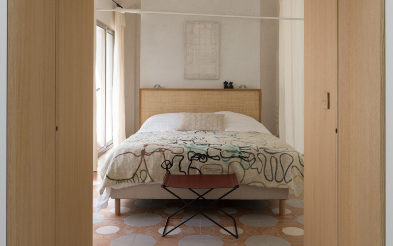 Camera da letto con pavimento a mosaico, letto con testata in legno e due porte in legno