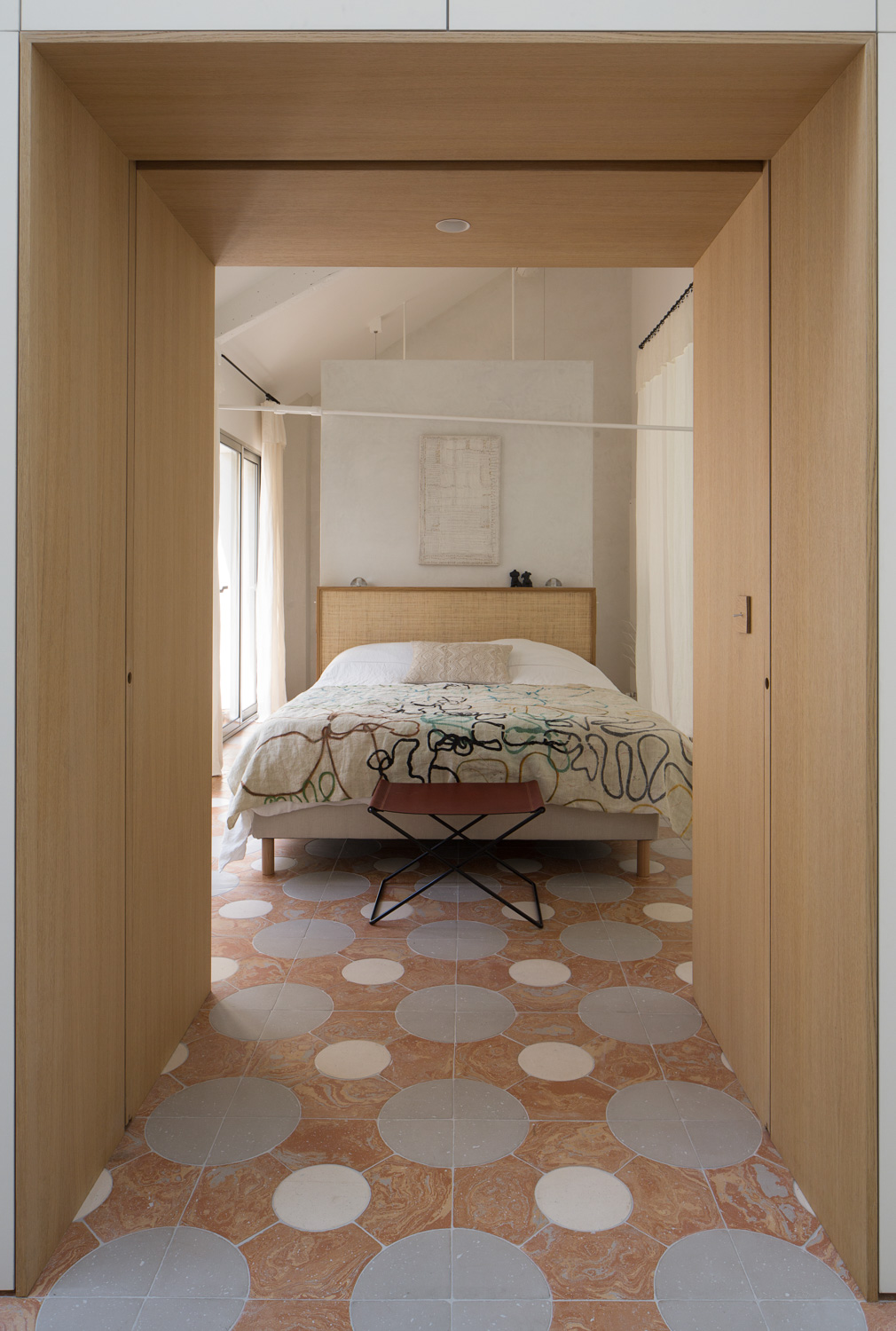 Camera da letto con pavimento a mosaico, letto con testata in legno e due porte in legno