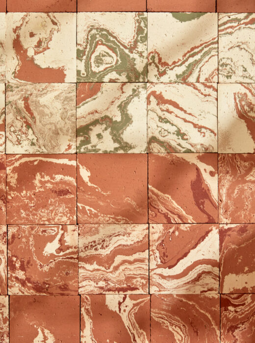 Rivestimento murale con piastrelle rettangolari in terracotta con venature marmoree.