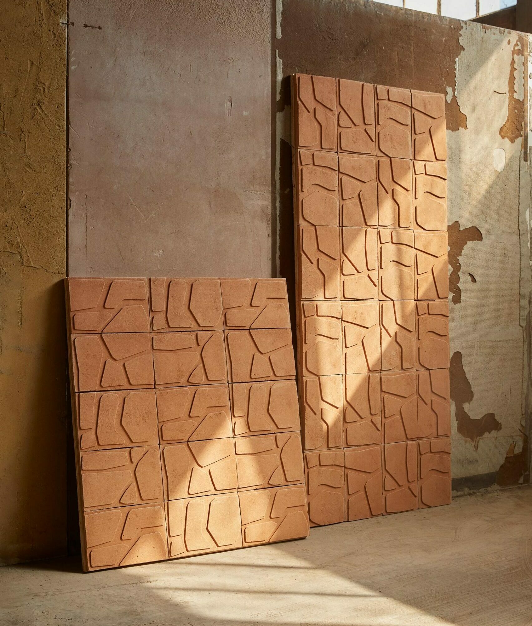 Rivestimenti murali in terracotta con piastrelle quadrate con motivo geometrico a rilievo.