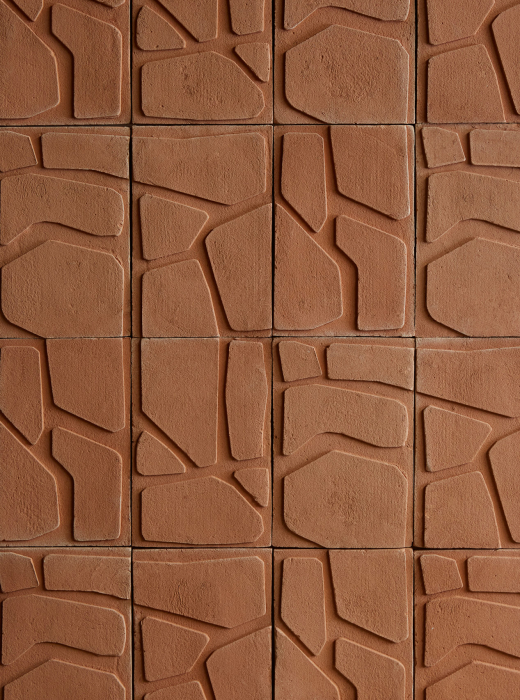Dettaglio di pannelli in terracotta con motivo geometrico inciso.