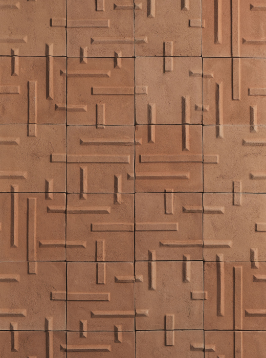 Parete rivestita con piastrelle in terracotta con motivo geometrico a linee orizzontali e verticali