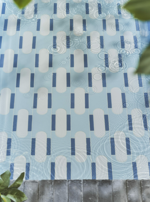 Pavimento azzurro con piastrelle bianche e blu sott'acqua, con riflessi e bolle in superficie