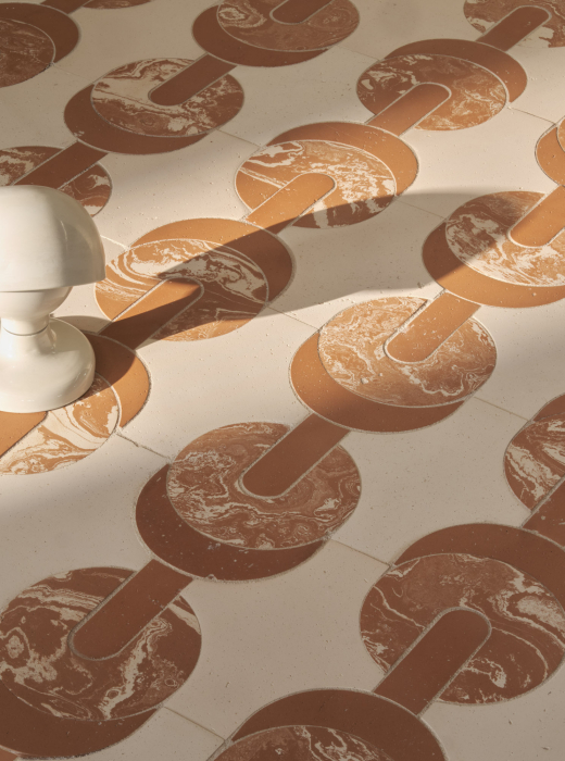 Pavimento con motivi circolari in terracotta su sfondo chiaro, decorato con finiture marmorizzate con lampada a sinistra