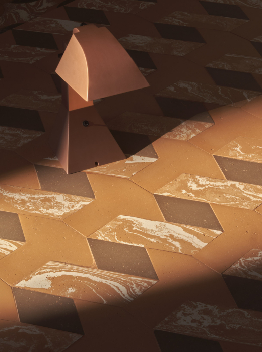 Pavimento in terracotta con motivi marmorizzati e lampada dal design geometrico in primo piano