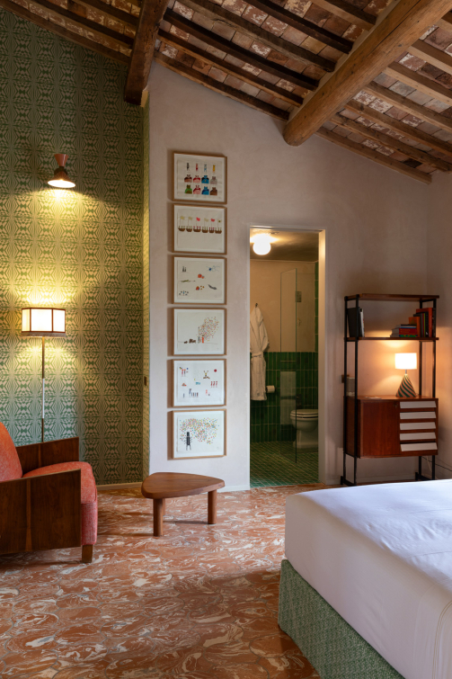 Sala con soffitto in legno, arredi colorati, tavoli in stile rustico e bancone rosa centrale