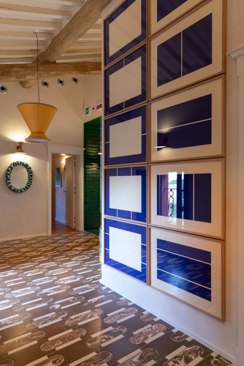 Interno con decorazioni geometriche blu, specchio circolare e pavimento decorato
